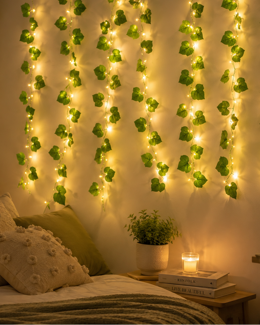Bedroom with decorative string lights and green leafy plants on the wall.